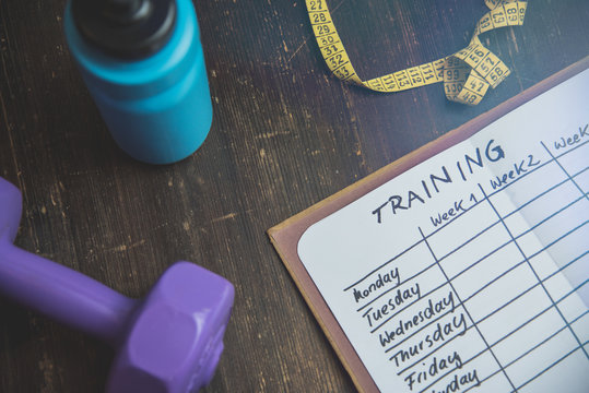 High Angle View Of A Workout Plan In Notebook At Wooden Desk