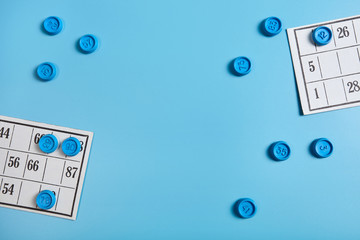 Bingo balls and cards on blue background with copy space.