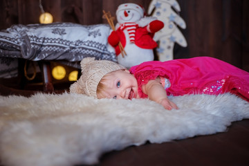 Obraz premium Funny baby girl lying on the carpet in the interior decorated for Christmas.