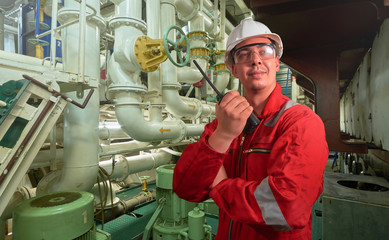 Ship's mechanic near marine diesel generators on a merchant ship in the engine room