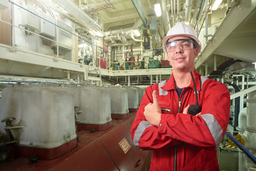 Ship's mechanic near marine diesel generators on a merchant ship in the engine room