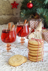 Christmas and new year holiday celebration concept background. Mug of mulled wine with spices, homemade nut cookie, shortbread, xmas tree decoration on wooden table