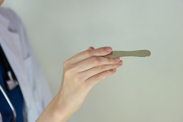 医者の診察シーン 舌圧子を手に持つ