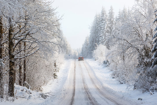 Slippery winter road with a car on a forest road