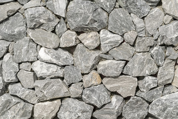 background, a wall of rough broken gray stones held on a clay cement Foundation