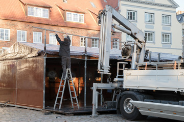 Fototapeta na wymiar preparation for the christmas market, man from behind is setting up a big tent in the city