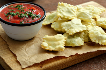 deliziosi ravioli fritti con salsa di pomodoro su sfondo tavolo di cucina