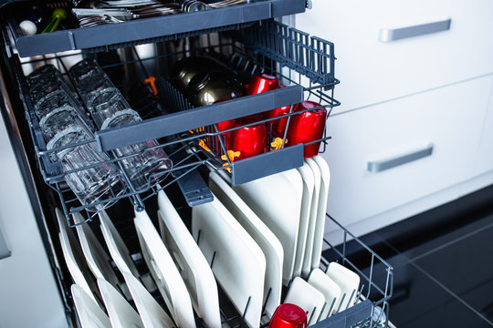 Modern open dishwasher with clean dishes in the kitchen.
