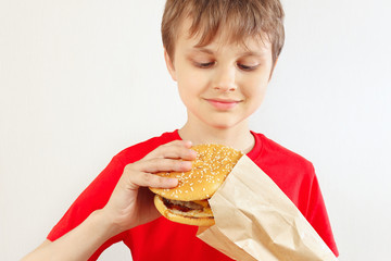 Young cut boy take out a hamburger from a package on a white background