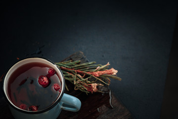 Treating cold. Hot tea with lemon and berries stands on white wooden table