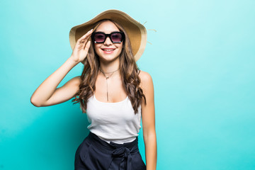 Elegant young attractive woman wearing summer clothes, straw hat and sunglasses, thinking about her summer vacation. Side view of woman with hand on chin, isolated over pastel blue background.