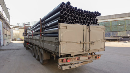 Old truck loaded with black plastic pipes. Back view. © Aleksandr