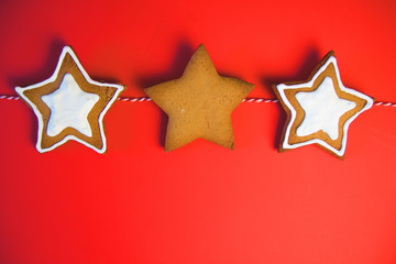 Fototapeta premium A row of three star cookies. Cookies tied a red ribbon. This fine handcrafted and painted by hand. Cookies in the shape of the star on red background.
