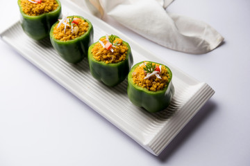 Stuffed capsicum or bharwa shimla mirchi is a popular Indian main course recipe. Served in a plate over moody background. Selective focus