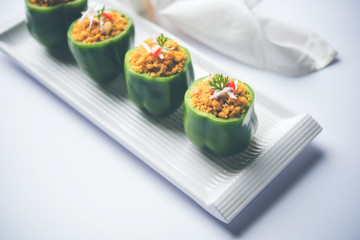 Stuffed capsicum or bharwa shimla mirchi is a popular Indian main course recipe. Served in a plate over moody background. Selective focus