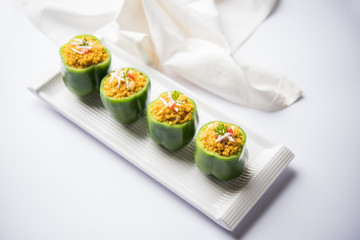Stuffed capsicum or bharwa shimla mirchi is a popular Indian main course recipe. Served in a plate over moody background. Selective focus