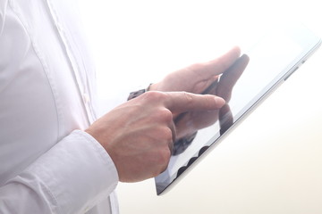 Man with white business shirt using tablet pad in front of a white background