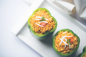 Stuffed capsicum or bharwa shimla mirchi is a popular Indian main course recipe. Served in a plate over moody background. Selective focus