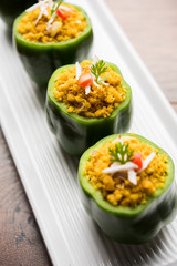 Stuffed capsicum or bharwa shimla mirchi is a popular Indian main course recipe. Served in a plate over moody background. Selective focus