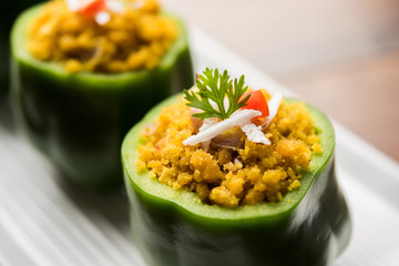 Stuffed capsicum or bharwa shimla mirchi is a popular Indian main course recipe. Served in a plate over moody background. Selective focus
