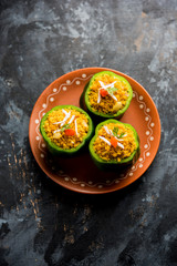 Stuffed capsicum or bharwa shimla mirchi is a popular Indian main course recipe. Served in a plate over moody background. Selective focus