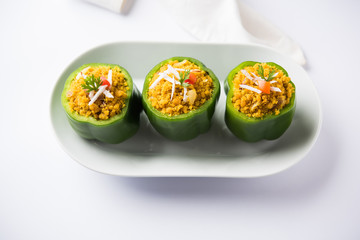 Stuffed capsicum or bharwa shimla mirchi is a popular Indian main course recipe. Served in a plate over moody background. Selective focus