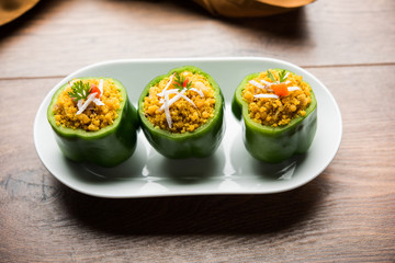 Stuffed capsicum or bharwa shimla mirchi is a popular Indian main course recipe. Served in a plate over moody background. Selective focus