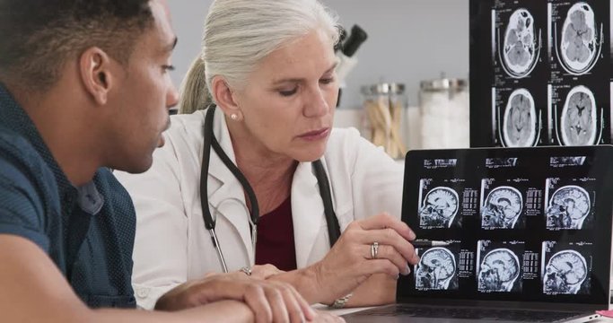 Close up of doctor consulting with patient on his concussion looking at ct scans of his brain