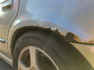 Brown rust over a wheel of a silver car 