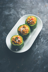 Stuffed capsicum or bharwa shimla mirchi is a popular Indian main course recipe. Served in a plate over moody background. Selective focus