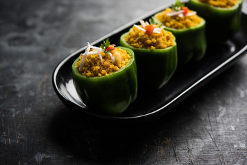 Stuffed capsicum or bharwa shimla mirchi is a popular Indian main course recipe. Served in a plate over moody background. Selective focus