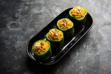 Stuffed capsicum or bharwa shimla mirchi is a popular Indian main course recipe. Served in a plate over moody background. Selective focus