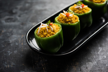 Stuffed capsicum or bharwa shimla mirchi is a popular Indian main course recipe. Served in a plate over moody background. Selective focus