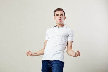 Full of energy joyful guy dressed in a white t-shirt and jeans happily shouts in the studio on a white background