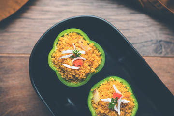 Stuffed capsicum or bharwa shimla mirchi is a popular Indian main course recipe. Served in a plate over moody background. Selective focus