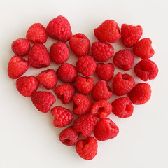Juicy fresh organic raspberries in the shape of a heart on a white background. Healthy food for a healthy life. Valentine's Day