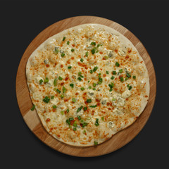 Appetizing pizza on a wooden board on a dark background. Classic feed.