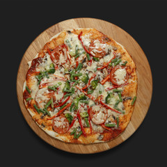 Appetizing pizza on a wooden board on a dark background. Classic feed.