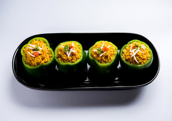 Stuffed capsicum or bharwa shimla mirchi is a popular Indian main course recipe. Served in a plate over moody background. Selective focus