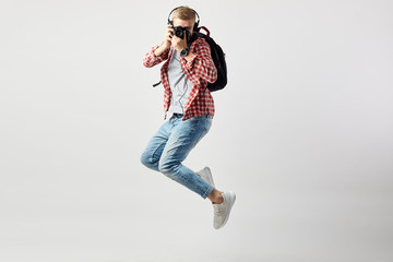 Blond guy in headphones, with black backpack on his shoulder dressed in a white t-shirt, red...