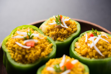 Stuffed capsicum or bharwa shimla mirchi is a popular Indian main course recipe. Served in a plate over moody background. Selective focus