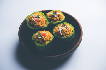 Stuffed capsicum or bharwa shimla mirchi is a popular Indian main course recipe. Served in a plate over moody background. Selective focus