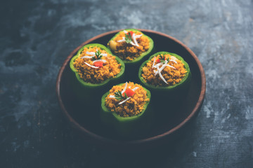Stuffed capsicum or bharwa shimla mirchi is a popular Indian main course recipe. Served in a plate over moody background. Selective focus