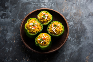 Stuffed capsicum or bharwa shimla mirchi is a popular Indian main course recipe. Served in a plate over moody background. Selective focus