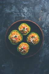 Stuffed capsicum or bharwa shimla mirchi is a popular Indian main course recipe. Served in a plate over moody background. Selective focus