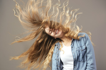 Nice girl with long brown flowing hair smiles on a gray background