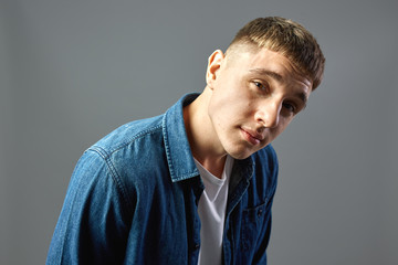 Portrait  guy dressed in white t-shirt and a jeans shirt on the gray background  in the studio