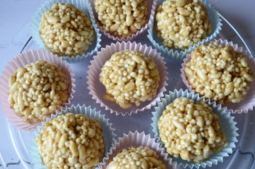 Closeup homemade cones made of puffed cereals, mainly rice and millet groats with fudge candy in colorful cupcake wrappers with blurred background