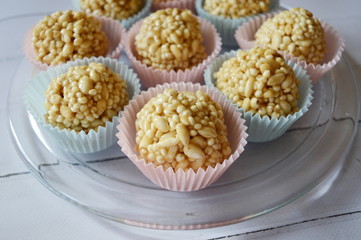 Closeup homemade cones made of puffed cereals, mainly rice and millet groats with fudge candy in colorful cupcake wrappers with blurred background