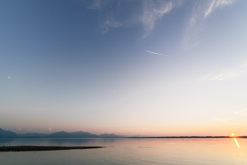 Sunset ion a bavarian lake with moon and sun at the same time